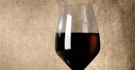 Egy pohár sötét bor, benne szőlőszemekkel