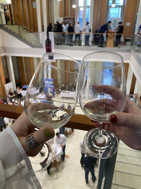 Emberek szakiköpenyben borokat kóstolnak és palackoznak